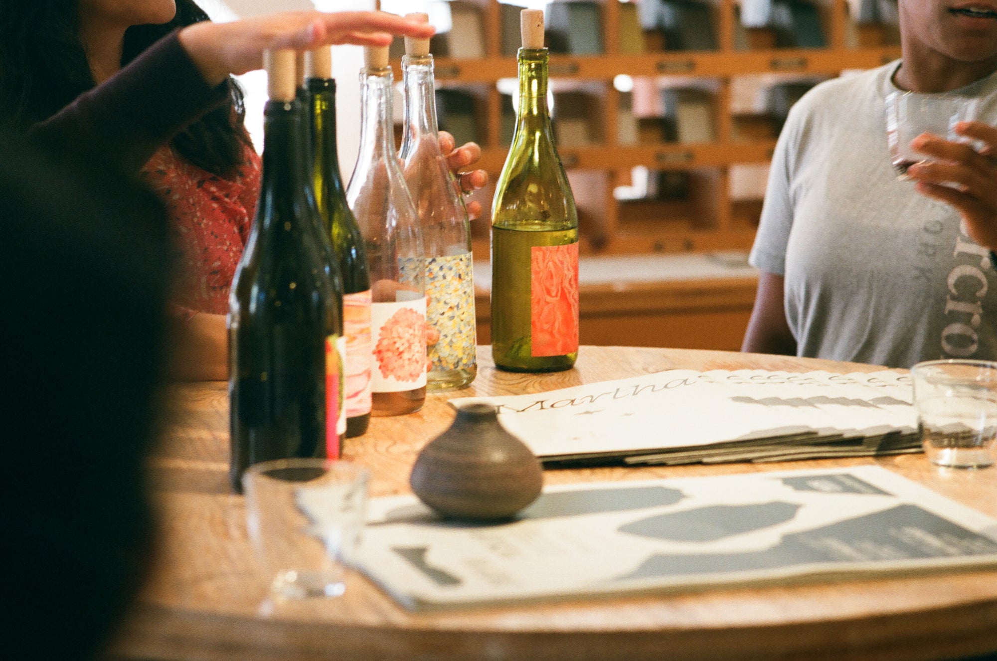 A hand rests on top of open (corked) bottles at a club-exclusive tasting and seasonal release pickup party at Heath Ceramics in San Francisco, CA.